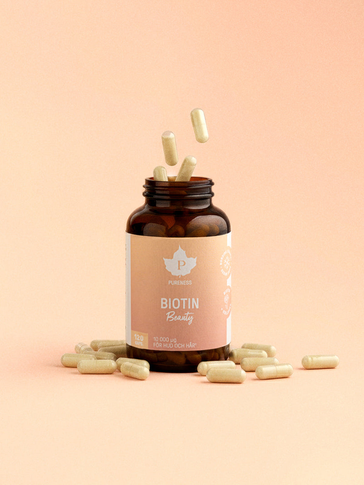 En burk biotin beauty med kapslar som flyger ut och en orange-rosa bakgrund