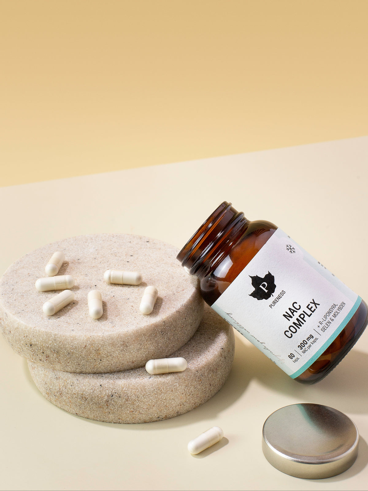 en öppnad burk NAC complex lutad mot en dekorationssten med kapslar utspritt på