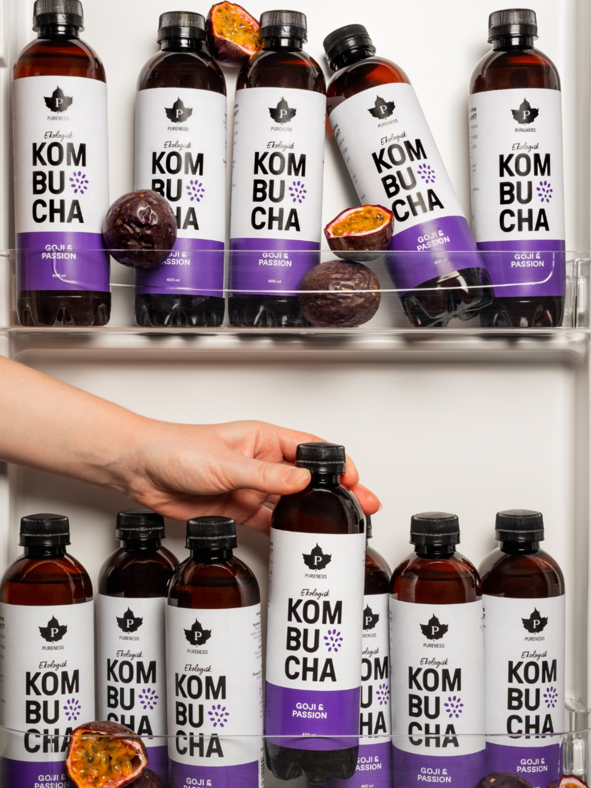 en kyl fylld med kombucha goji passion och passionsfrukter med en hand som tar en av dem