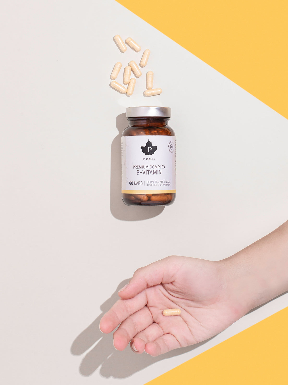 en burk premium complex b-vitamin med en hand under som har en kapsel i sig