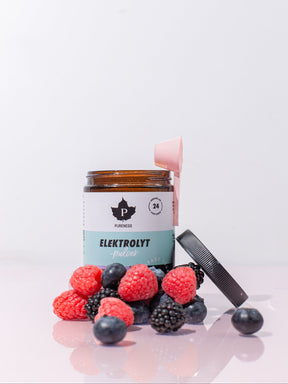 En öppnad burk elektrolytpulver skogsbär med skogsbär som ligger framför burken